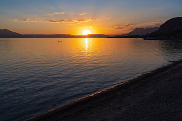 Naklejka premium sun sets behind mountains surrounding lake chapala and illuminates water