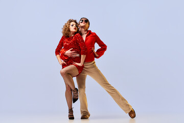 Young flexible couple of dancers in bright retro fashion clothes, stage costumes dancing over light background. Concept of music, art, dance, retro