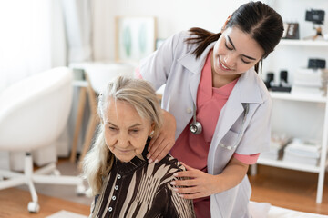 Fototapeta premium Doctor woman take care smiling older caucasian woman of shoulder massage home