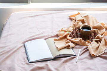 Coffee cup, bamboo tray and open notebook on bed. Good springtime morning.