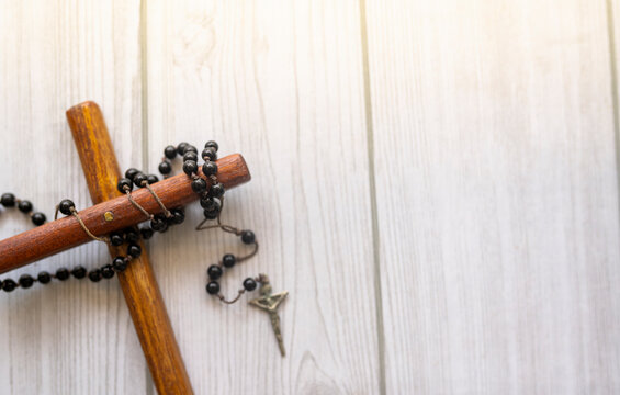 Christian cross of wood and black prayer beads in light background of wooden texture, National Christian day concept Selective focus