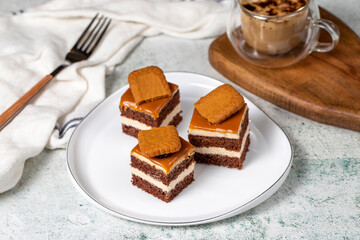 Small dessert cakes. Caramel petit four on a white plates in dark background. Biscuit french petit four cake