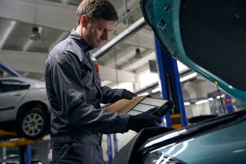 Man holding parts for car repair in workshop