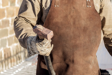 In the blacksmith's male hand is a copper old working hammer.