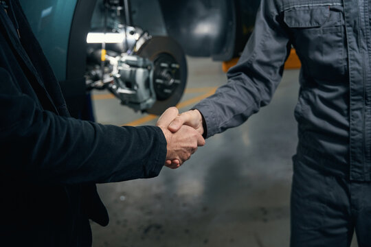 Mechanic talking with client and shaking hands