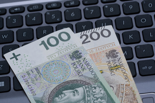 Dwa polskie banknoty położone na klawiaturze laptopa