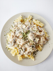 Pasta with chicken and mushrooms in creamy cheese sauce on a white background