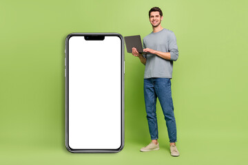 Full body photo of brown haired businessman promote smartphone placard isolated on green color background