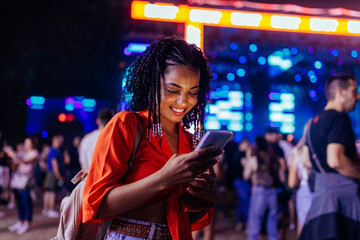 Young girl with smartphone at music festival.