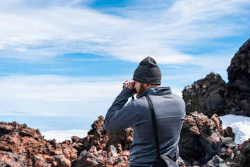 Joven hombre turista con ropa de invierno fotografiando paisaje rocoso con vistas increíbles del...