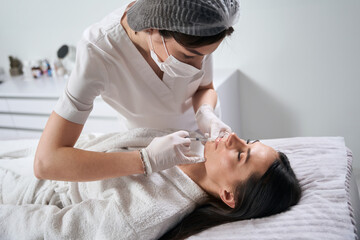 Young lady on injection procedure in cosmetology cabinet