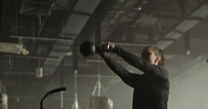 Motivated sportswoman doing kettlebell swing exercise in gym