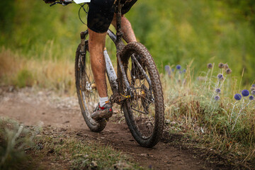 dirty feet and mountain bike male athlete mountainbiker. riding on forest trail. cross-country...