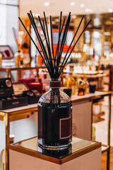 Fototapeta na wymiar Black glass bottle with wood stick aroma diffusers on mirror stand in the shopping mall Home decoration. Minimalist air freshener concept. Vertical