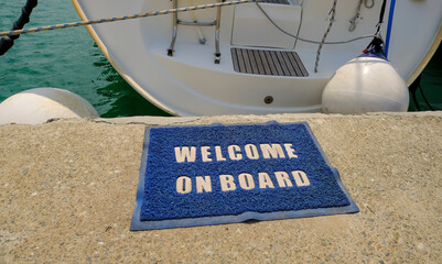 Welcome on board text on carpet across the sea and boat in the harbor. transportation