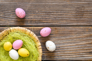 Easter eggs in a decorative nest on a wooden background, top view.
