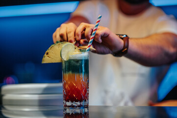 Obraz premium Barkeeper bereitet Cocktail vor und Steckt Ananas an Cocktailglas