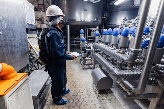 Male work inspection process stainless steel tanks and pipe with pressure meter in equipment tank facility for milk cellar at the with vertical stainless mixing tank