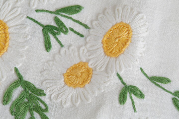 Fototapeta na wymiar Embroidery with daisies. Vintage fabric with flower design. Close-up detail.
