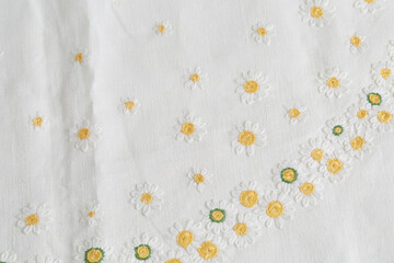 Embroidery with daisies. Vintage fabric with flower design. Close-up detail.