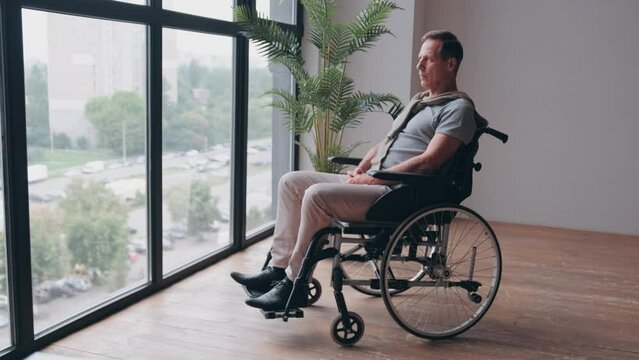 Senior man sitting in wheelchair near window at home