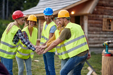 A group of builders are rising team spirit at a construction site in the forest. Construction,...