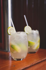 Brazilian Caipirinhas made with sugar, lemon and cachaça on a wooden table.