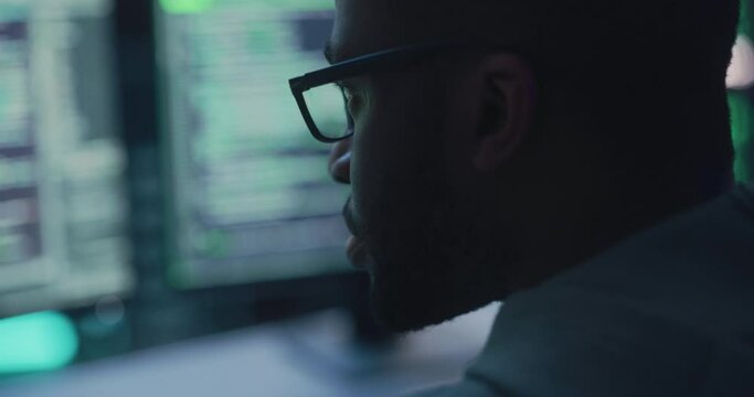 Close Up Portrait of Black Male Programmer Looking at Desktop Computer Display Monitors. Professional Developer Writing Code, Working on High Tech Project. Coding and Developing Job Concept