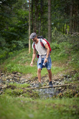 Young man Crossing River.Journey in the forest. Healthy lifestyle