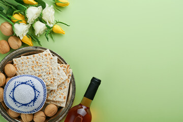 Obraz na płótnie Canvas Passover celebration concept. Matzah, kosher red wine, walnut and spring white and yellow rose flowers. Traditional ritual Jewish bread on light green background. Passover food. Pesach Jewish holiday.