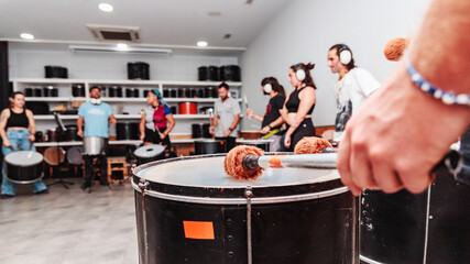 Percussion mace on drum, in the background batucada class students out of focus