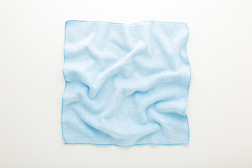 Light blue wrinkled dry soft microfiber rag for different surfaces wiping on white table background. Top down view. Closeup.