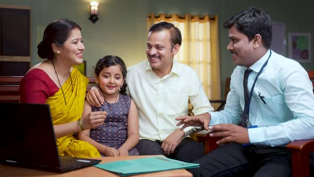 Happy smiling couple with kid receiving new home keys from banker after contract or deal at home - concept of mortgage, property investment and doorstep banking service