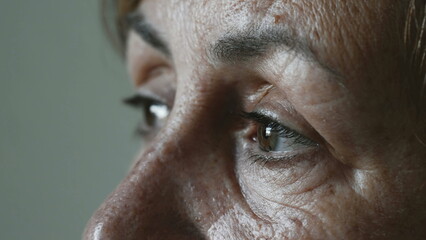 Thoughtful senior woman closeup eyes dreaming awake. One pensive older lady in 70s. Macro eye of a female mature person. Dramatic expression