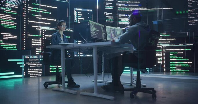 Diverse Young Man and Woman Working on Desktop Computers, Surrounded by Big Screens Displaying Code Lines. Professional Computer Engineers Developping Autonomous Algorithm for Generative AI