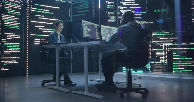 Portrait of Two Programmers Working in a Monitoring Control Room, Surrounded by Big Screens Displaying Lines of Programming Language Code. Portrait of Diverse Developers Creating a Software and Coding