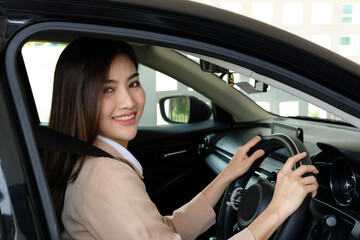 Naklejka premium Beautiful happy successful businesswoman is driving a new modern car in good mood. Portrait cute female driver steering car with safety belt.