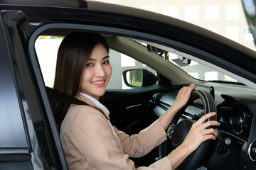 Fototapeta na wymiar Beautiful happy successful businesswoman is driving a new modern car in good mood. Portrait cute female driver steering car with safety belt.