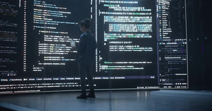 Back View Shot of Female Programmer Working in a Monitoring Control Room, Surrounded by Big Screens Displaying Lines of Programming Language Code. Portrait of Woman Creating a Software and Coding