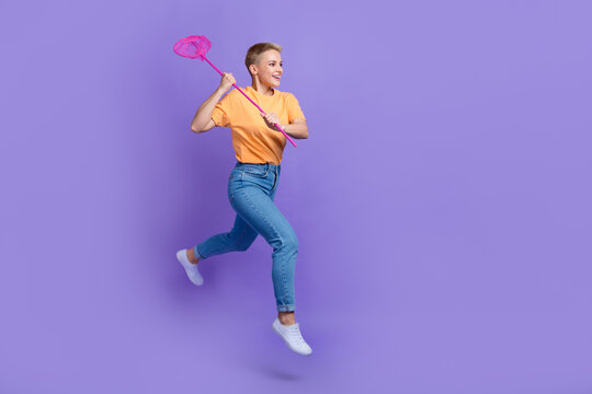 Full length photo of excited optimistic nice girl dressed jeans white sneakers hunting butterflies isolated on violet color background