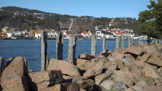 Old wooden breakwaters along the shore of Drammen Fjord. On the opposite shore is the town of Svelvik