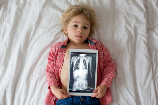 Toddler Child, Holding X-ray Picture On Tablet Of Child Body With Swallowed Magnet Showing, Child Swallow Dangerous Object