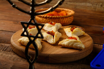 cookies triangles gometashi mishloach manot for Purim laid out on a wooden board menorah in the foreground.