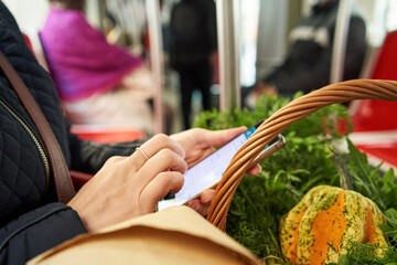 Woman returning from farmers market on a tram, looking at her phone
