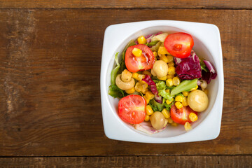 Vegetable salad with champignon corn and cherry tomato with avocado in a white plate. save a place.