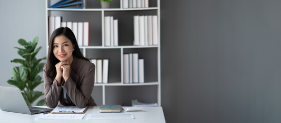 Portrait of young pretty Asian businesswoman working and smiling to the camera.