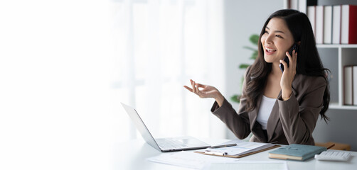 Portrait of young Asian businesswoman having a phone call with her client in office room.