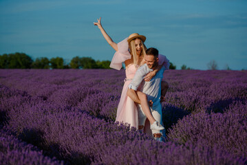 a woman in a pink dress and hat and a man in a white shirt are walking in a lavender field..