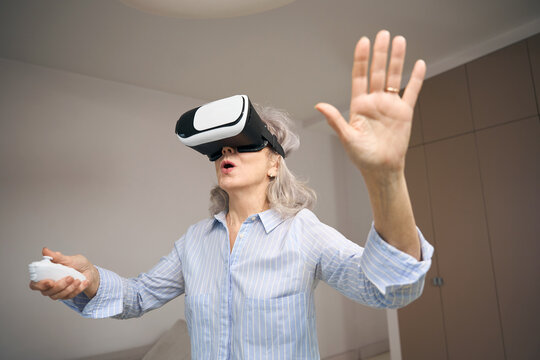 Modern grandmother at home in virtual reality glasses