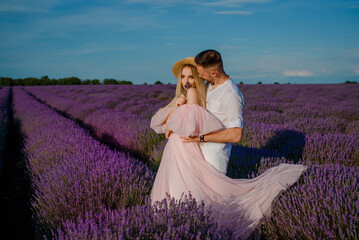Fototapeta premium a woman in a pink dress and hat and a man in a white shirt are walking in a lavender field..